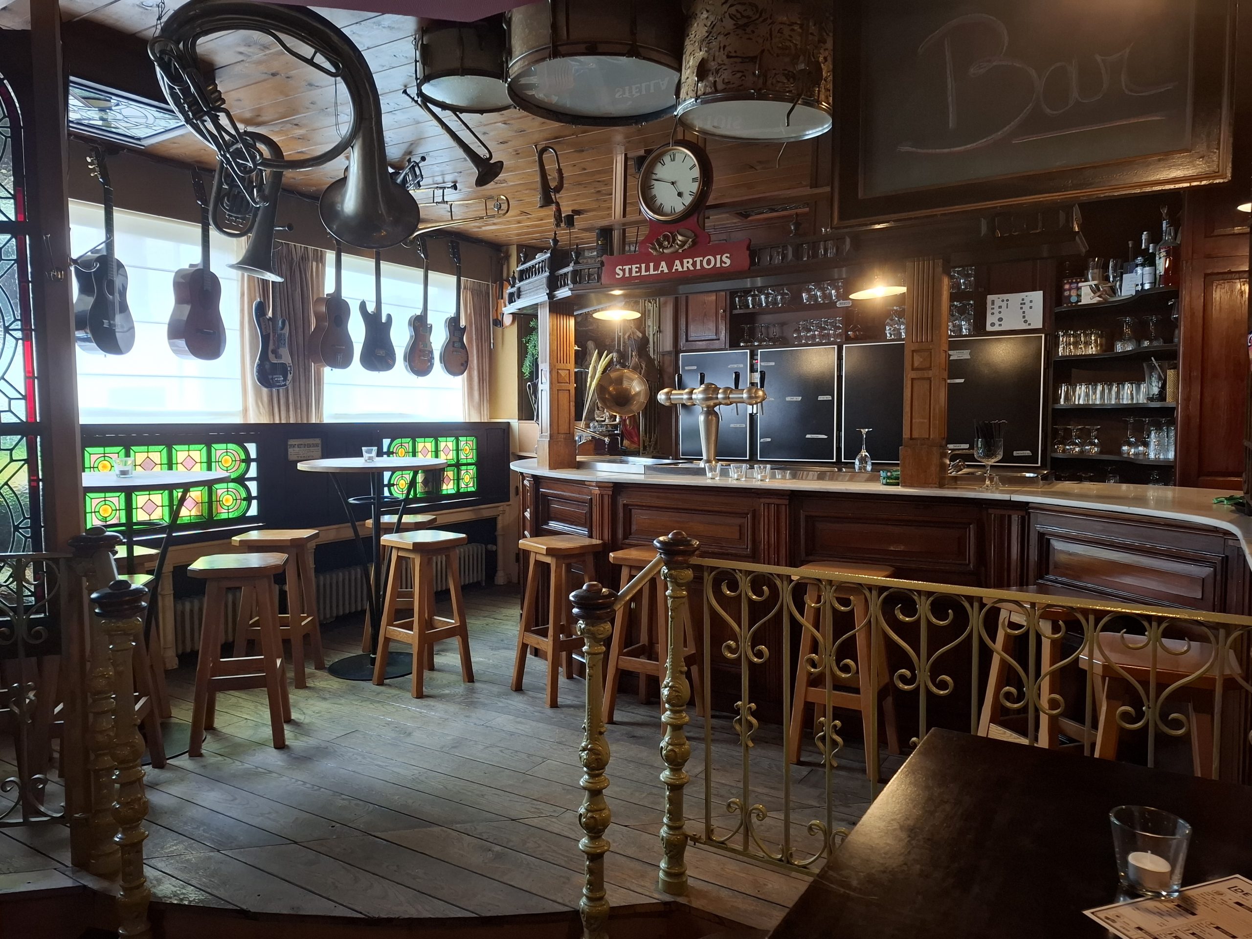 De bar van De Kluze met gitaren en koperinstrumenten aan het plafond